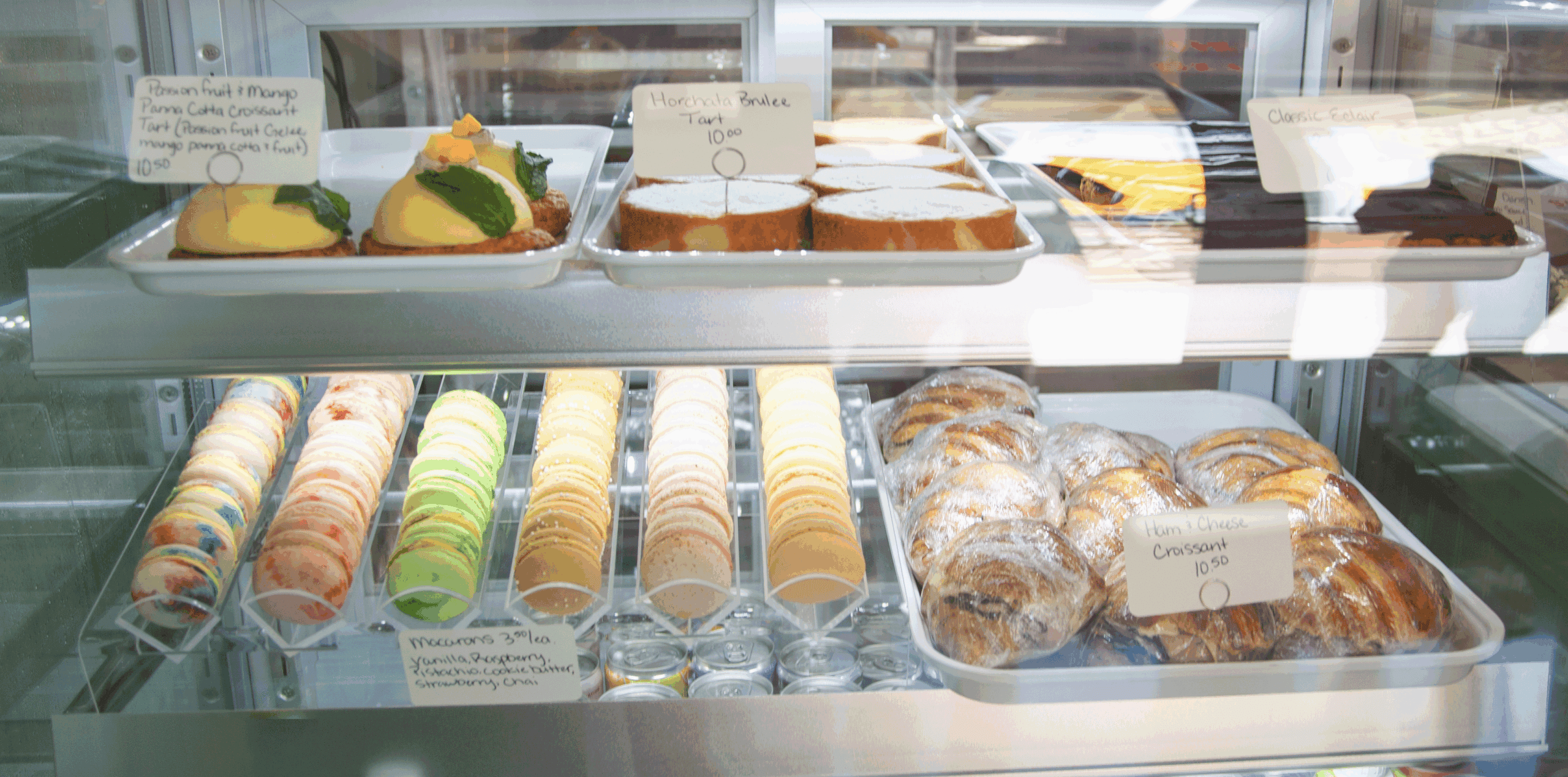 Bakery display case with colorful macarons and assorted pastries, including croissants and tarts