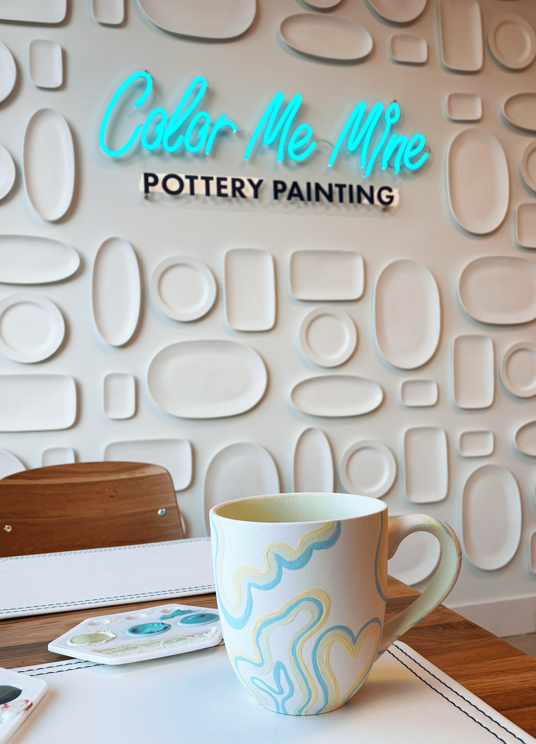 Hand painted mug against a Color Me Mine photo wall. 
